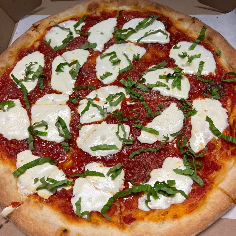 Close-up of a Casa di Franco Pizzeria Margherita pizza with fresh mozzarella, red sauce, and basil.