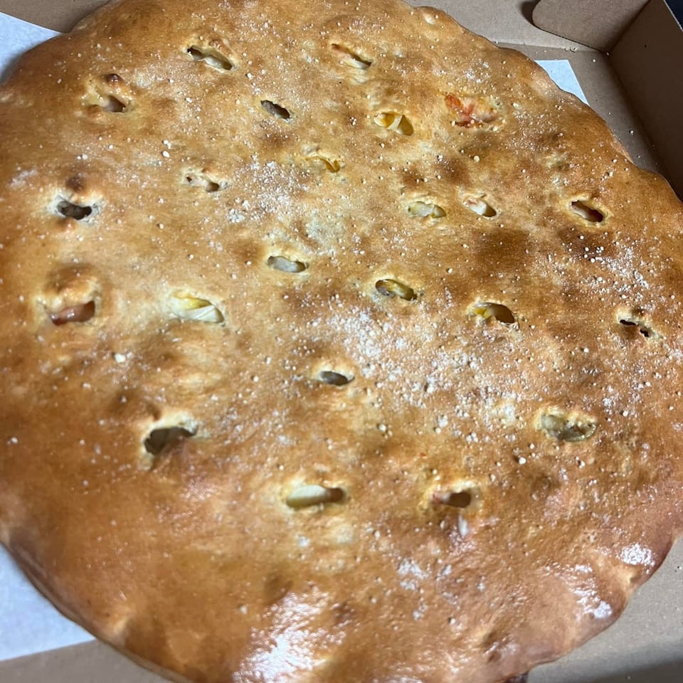A golden-brown calzone from Casa di Franco Pizzeria, sprinkled with salt and baked to perfection.